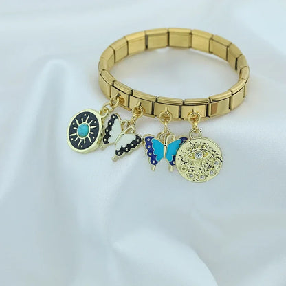Butterfly Heart Eye golden charms – gold Italian charm bracelet with eye disc and butterfly charms displayed on fabric, Italian charm bracelet lifestyle photo by Charmtastic