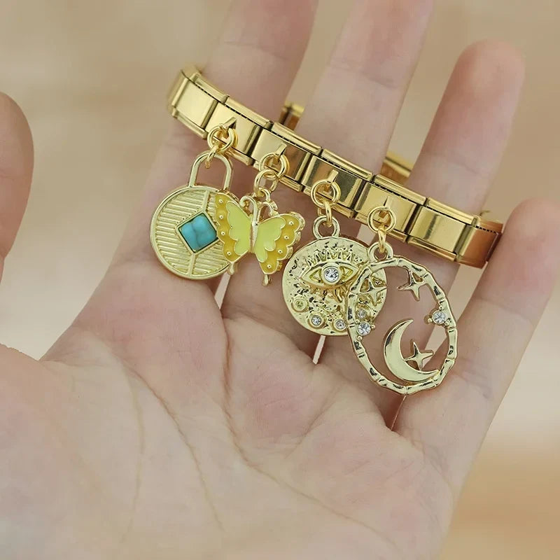 Butterfly Heart Eye golden charms – gold Italian charm bracelet with turquoise disc, butterfly, and moon star charms held in hand, Italian charm bracelet lifestyle photo by Charmtastic