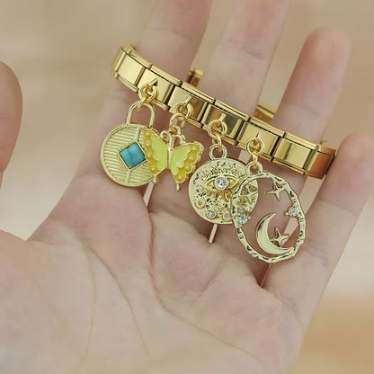 Butterfly Heart Eye golden charms – gold Italian charm bracelet with turquoise disc, butterfly, and moon star charms held in hand, Italian charm bracelet lifestyle photo by Charmtastic