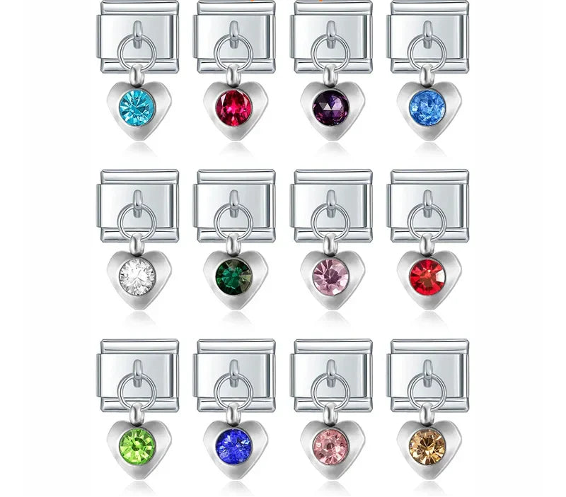 A collection of 9mm silver Italian charms featuring puffy heart dangles. Each heart is centered with a large, faceted round crystal available in 12 colorful birthstone options.