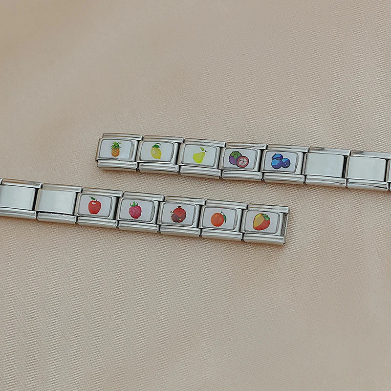 Fruits Italian Charms – two unassembled charm chains on cream fabric showing pineapple, lemon, pear, mangosteen, and blueberries on one chain, and apple, strawberry, raspberry, orange, and strawberry on the other, Italian charm bracelet charms by Charmtastic