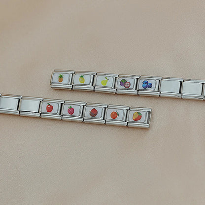 Fruits Italian Charms – two unassembled charm chains on cream fabric showing pineapple, lemon, pear, mangosteen, and blueberries on one chain, and apple, strawberry, raspberry, orange, and strawberry on the other, Italian charm bracelet charms by Charmtastic