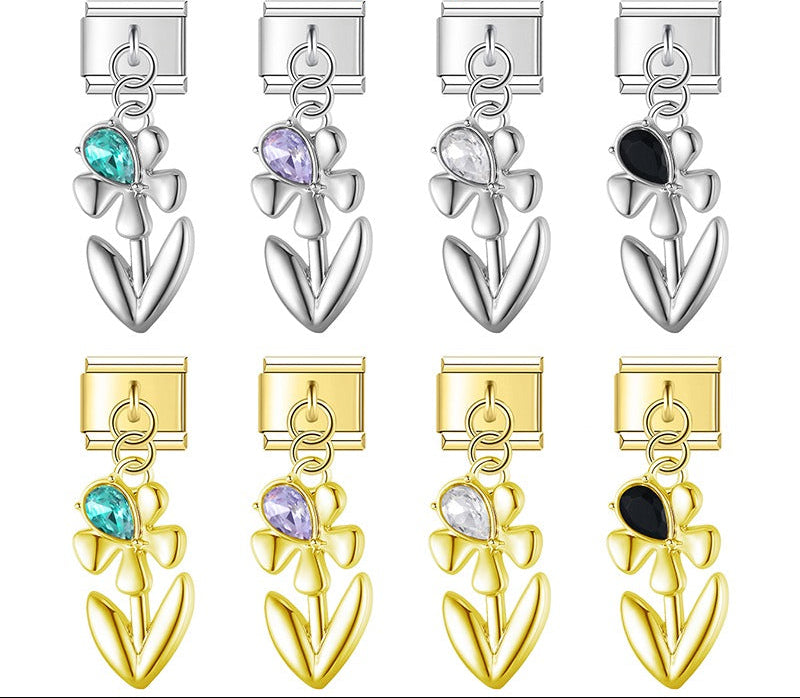 A 9mm Italian charm featuring a sleek metal flower dangle with a teardrop crystal accent. Available on silver and gold bases with teal, purple, clear, and black gems.
