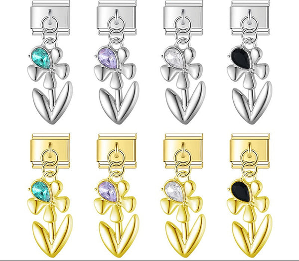A 9mm Italian charm featuring a sleek metal flower dangle with a teardrop crystal accent. Available on silver and gold bases with teal, purple, clear, and black gems.