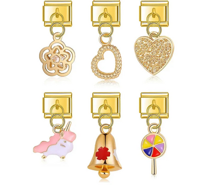 A collection of 9mm gold Italian charms featuring dangles of a crystal flower, rope heart, filigree heart, pastel unicorn, red cross bell, and colorful lollipop.