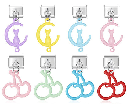 A 9mm silver Italian charm featuring a glossy, open-cutout dangle of either a cat on a moon or a pair of cherries. Available in pastel purple, yellow, blue, pink, green, and red.