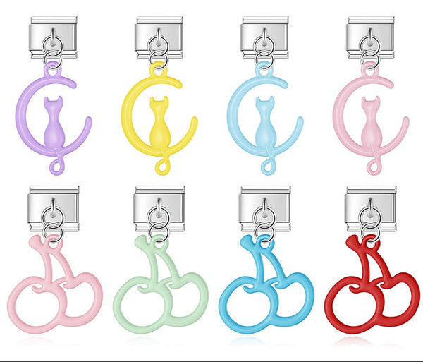A 9mm silver Italian charm featuring a glossy, open-cutout dangle of either a cat on a moon or a pair of cherries. Available in pastel purple, yellow, blue, pink, green, and red.